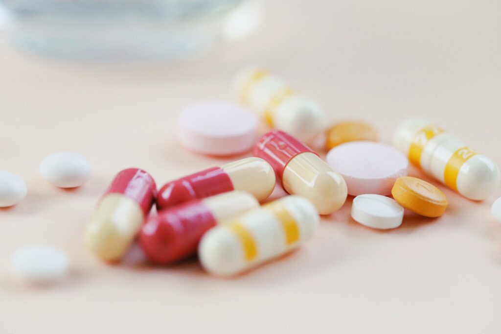 Pile of pharmacy drugs and blur glass closeup on yellow background