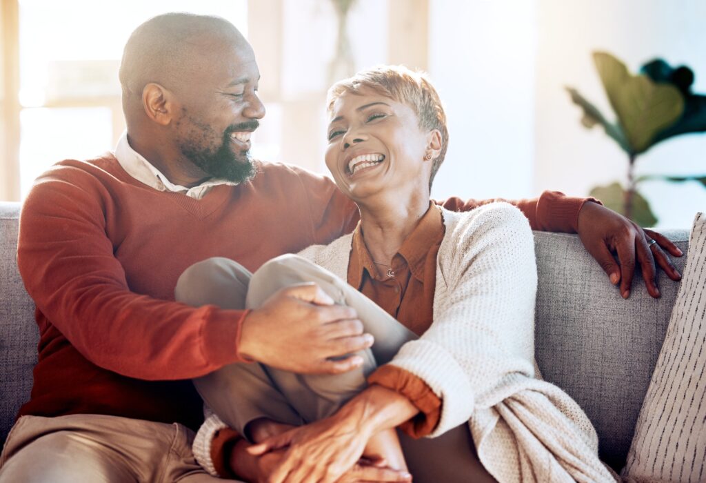 Relax, happy and love with black couple on sofa for retirement, support and smile together. Marriag